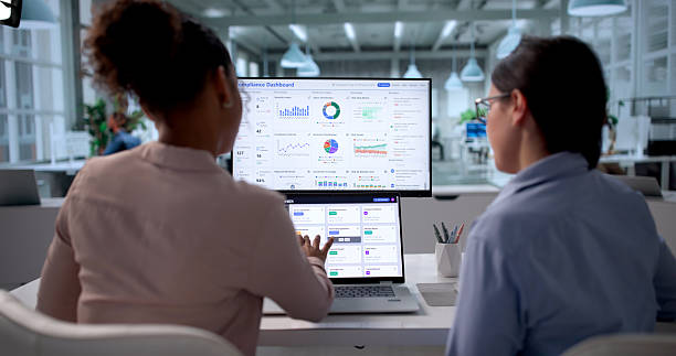 Duas pessoas analisando dashboards em telas de computador